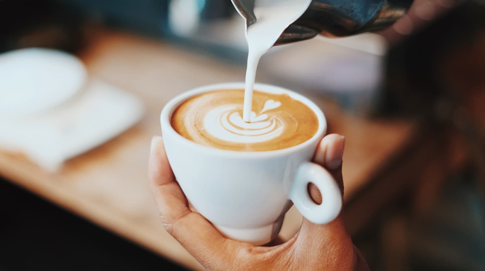 Barista häller upp mjölkskum till en cappuccino